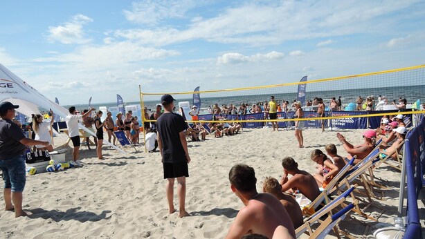 Una partita di pallavolo sulla spiaggia con spettatori e giocatori.