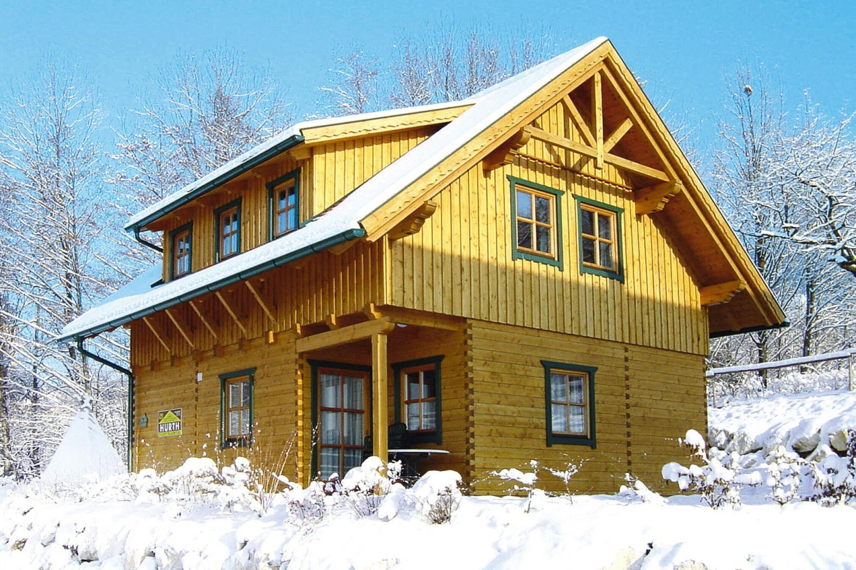 A wooden cabin with a gabled roof, multiple windows, and a porch.