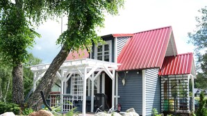 A house with a red roof, a porch with a white railing, and a stone wall in front. - Holiday Home Near Lake Mausz With Sauna (Parchowo)