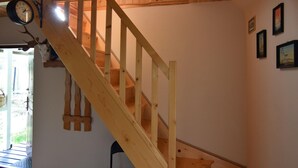 A wooden staircase with a clock above it, a door leading outside, and a wall with framed pictures. - Holiday Home Near Lake Mausz With Sauna (Parchowo)