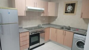 Een kleine keuken met een koelkast, fornuis, oven, spoelbak en wasmachine.