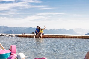 A couple sitting on a wooden dock extending into a body of water, with mountains in the background. - Apartment in Fugen Near Spieljoch Ski Lift (Fuegen)