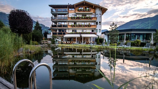 A multi-story hotel with balconies, a reflection pool, and a wooden deck. - Apartment in Fugen Near Spieljoch Ski Lift (Fuegen)