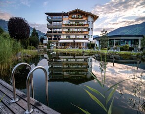 Un hôtel à plusieurs étages doté de balcons, d’un bassin décoratif et d’une terrasse en bois.