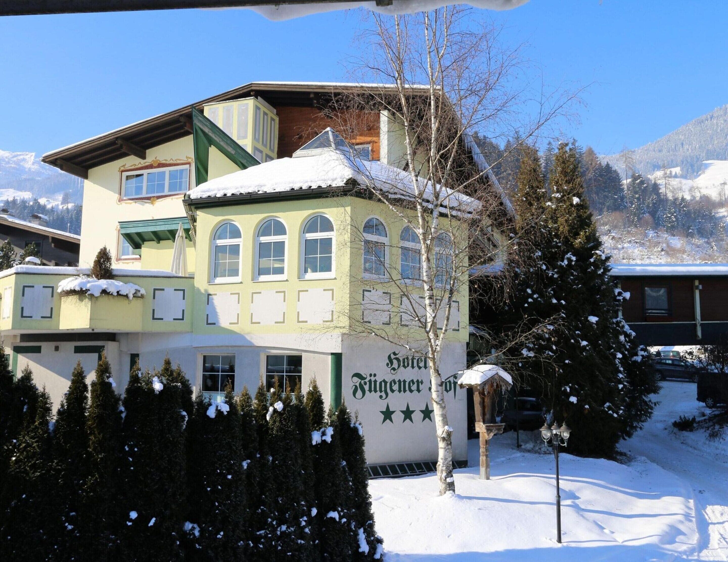 A hotel with a snow-covered roof and a sign indicating it is a "Hotel Tuggen."