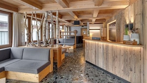 A wooden interior with a reception desk, seating area, and a stone-tiled floor. - Apartment in Fugen Near Spieljoch Ski Lift (Fuegen)