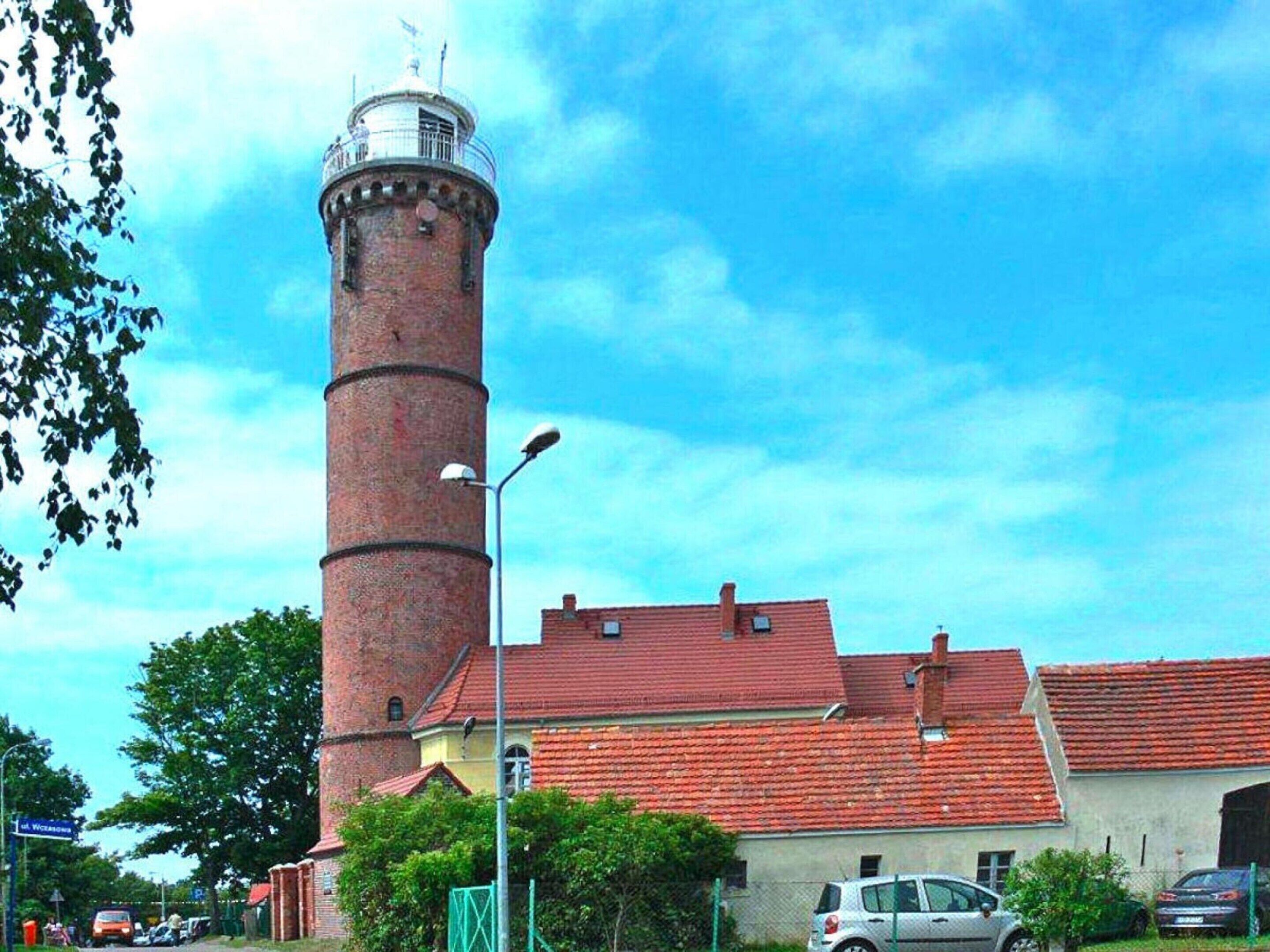 A brick tower with a red roof, a street lamp, and a building with a similar red roof.