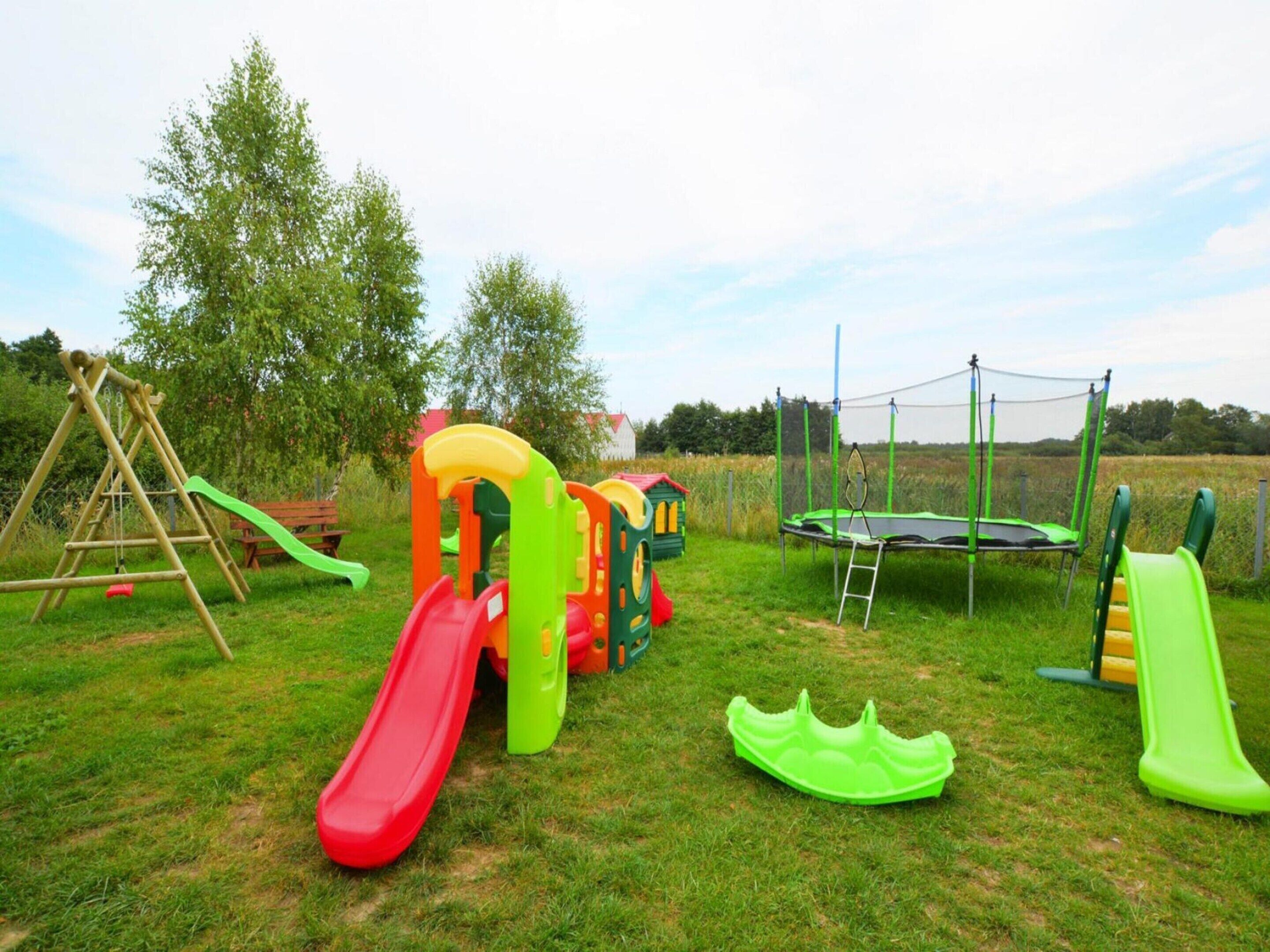 A playground with a swing set, a slide, a trampoline, and a climbing structure.