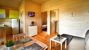 Una cabaña compacta con comedor, kitchenette, sala de estar y dormitorio.