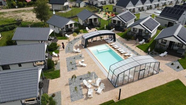 Zona residencial con casas modernas, piscina y mobiliario exterior.