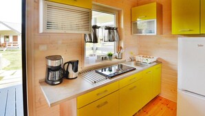 Una cocina compacta con armarios amarillos, un lavamanos de acero inoxidable y un refrigerador blanco.