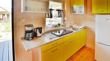 A compact kitchen with yellow cabinets, a stainless steel sink, and a white refrigerator.
