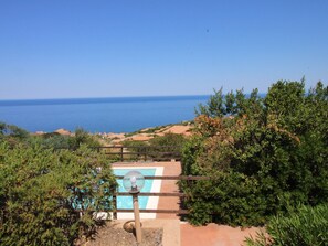 Vue d’une piscine, avec un ciel bleu clair et l’océan en arrière-plan.