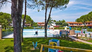 A pool area with a fenced swimming pool, a children's play structure, and a grassy lawn. - Residence Villaggio Danubio, Bibione Spiaggia (San Michele al Tagliamento)