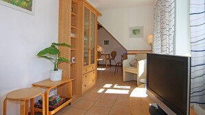 A living room with a TV, wooden furniture, a potted plant, and a staircase leading to another room. - Appartementhaus Kranichblick, Breege (Breege)