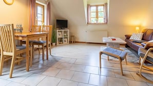 A spacious living area with a wooden dining table, chairs, a sofa, and a TV. - Landhaus in Vollerwiek (Vollerwiek)