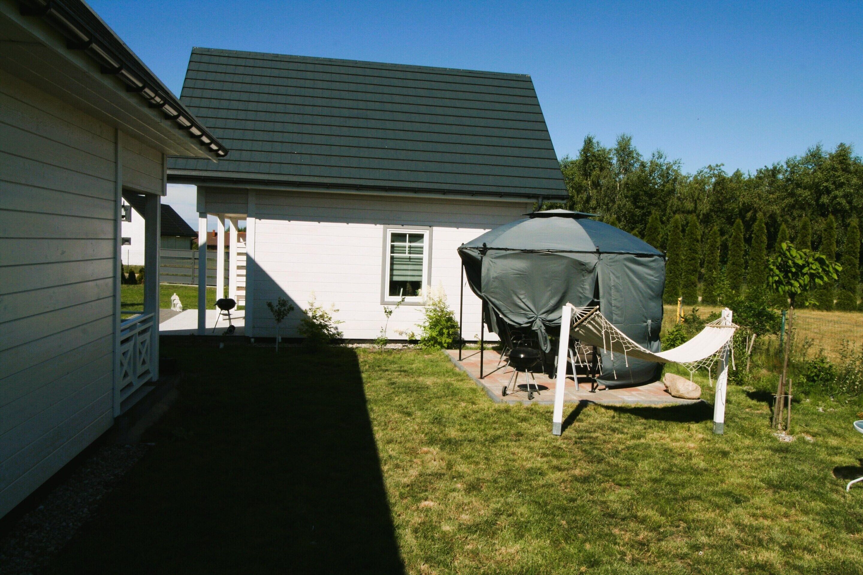 Una casa con un espacio exterior cubierto, una hamaca y una parrilla.