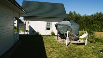 Una casa con un espacio exterior cubierto, una hamaca y una parrilla.