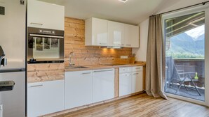 A modern kitchen with white cabinets, a wooden backsplash, and a built-in oven. - Chalet in Neukirchen With Mountain Views (Neukirchen am Grossvenediger)