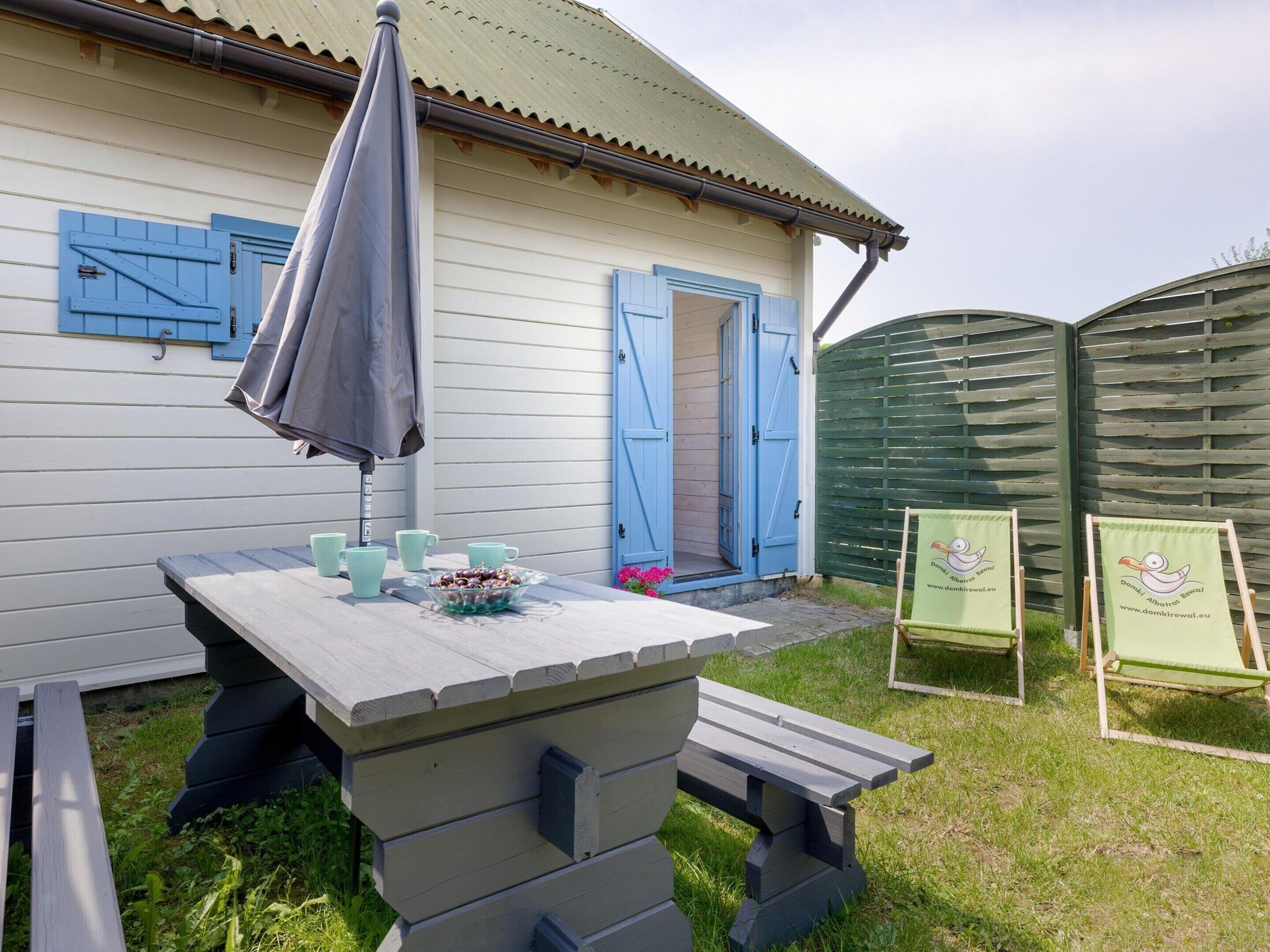 Une table en bois avec un banc, un parasol gris et un bol de collations.