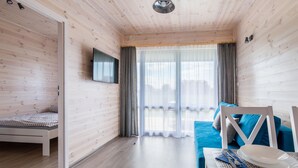 Un'accogliente stanza con un letto, un divano blu, un tavolo da pranzo con piatti e un televisore montato a parete.