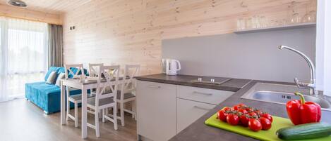 A modern kitchen with a dining area, wooden ceiling, and a view to the living room.