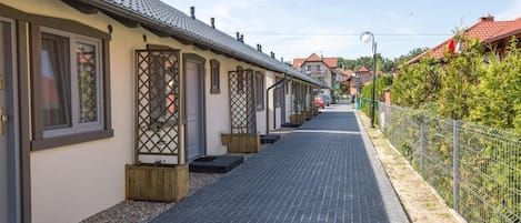 A row of traditional-style buildings with a paved walkway and a metal fence on one side.
