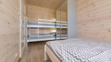 Una habitación con literas, un armario y una cama con cubrecama estampado.