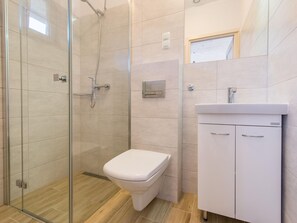 Bathroom features a glass-enclosed shower, toilet, sink, and mirror.
