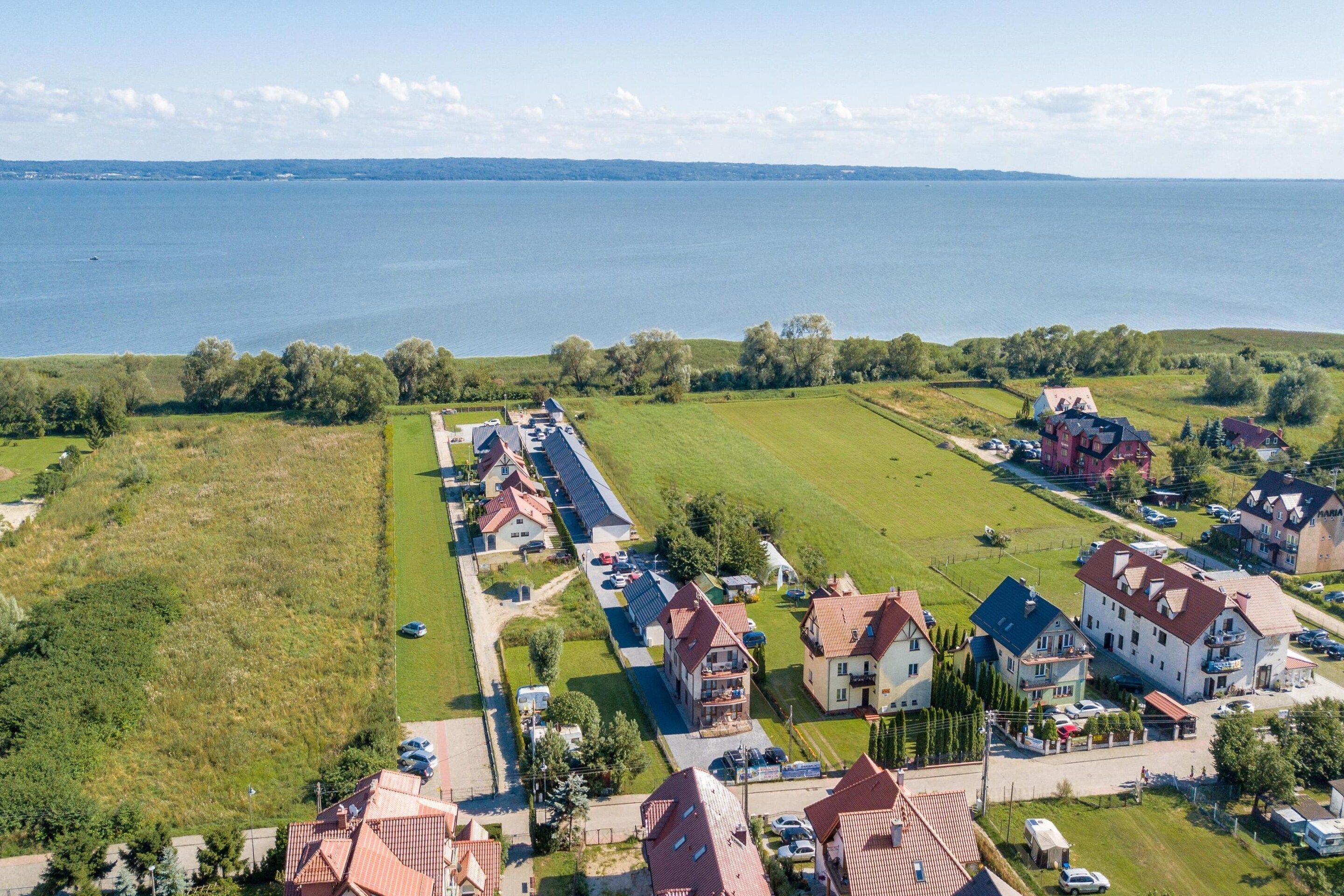 Un quartier résidentiel avec des maisons, une route et une étendue d’eau en arrière-plan.