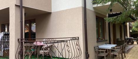 A courtyard with a green lawn, a table and chairs, and a railing.