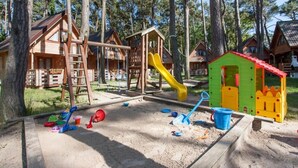 Ein Spielplatz mit Rutsche, Schaukeln und Sandkasten.