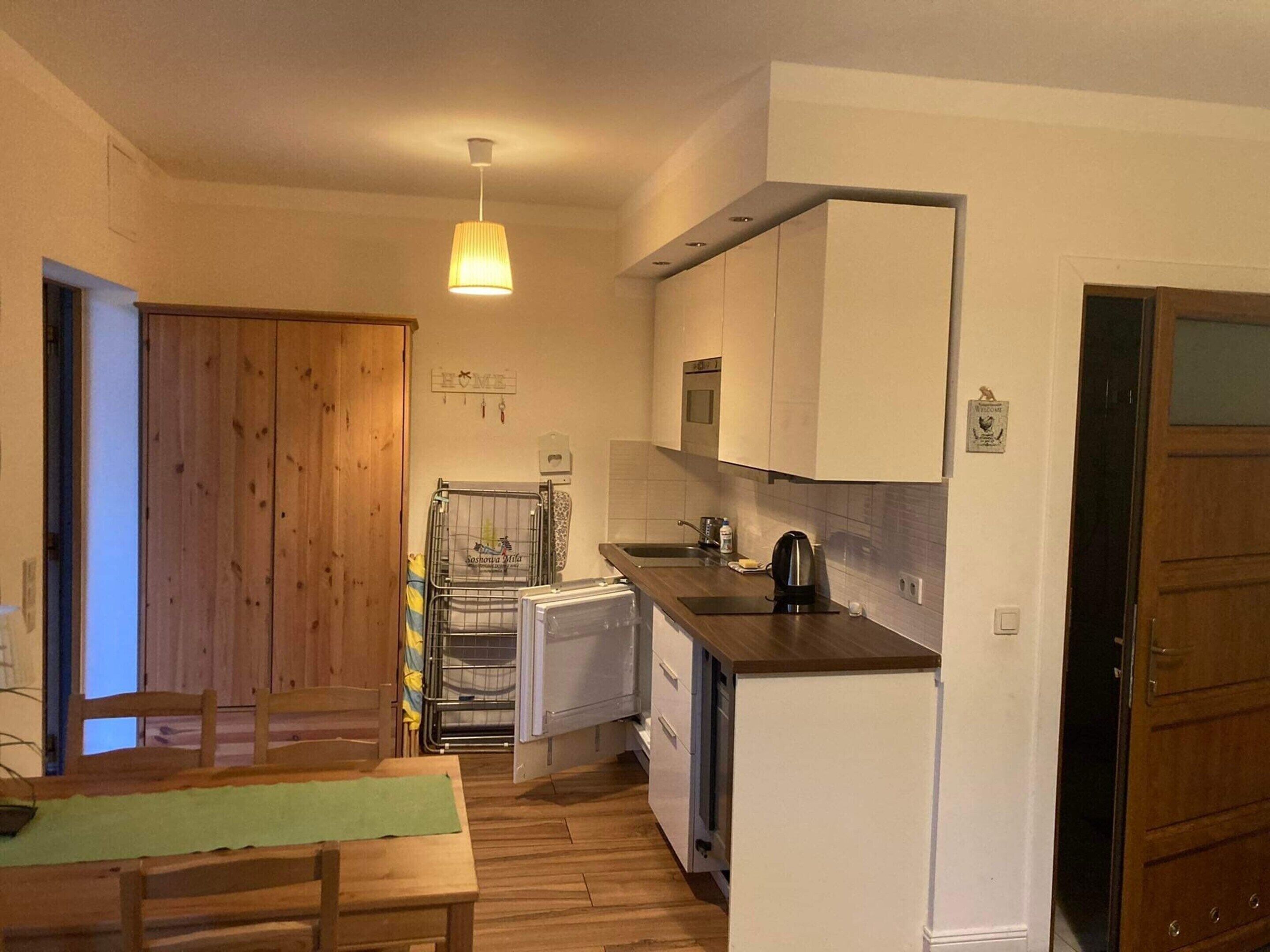 A compact kitchen with wooden cabinets, a small refrigerator, a coffee maker, and a dining area with a table and chairs.