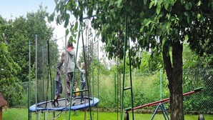 Un parque infantil con un trampolín, columpios y una estructura para escalar.