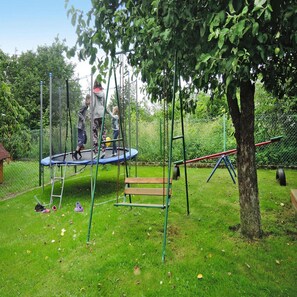 A playground with a trampoline, swings, and a slide. - Holiday Home in Kolczewo Near Baltic Sea (gmina Wolin)