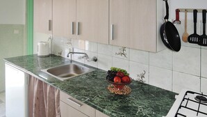 Una cocina con encimera de mármol, pileta de acero inoxidable y cocina a gas.