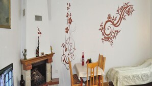 Una sala de estar con chimenea, una mesa de comedor con sillas, una cama y un televisor sobre un mueble de madera.