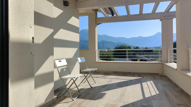 A balcony with a view of mountains, two white chairs, and a tiled floor. - Holiday Home Casa Simone in Lido (Camaiore)