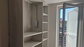 A room with a sliding glass door leading to a balcony, a built-in closet with multiple shelves, and a light fixture. - Holiday Home Casa Simone in Lido (Camaiore)