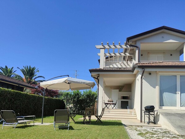 A two-story house with a balcony, a patio with outdoor furniture, and a clear blue sky.