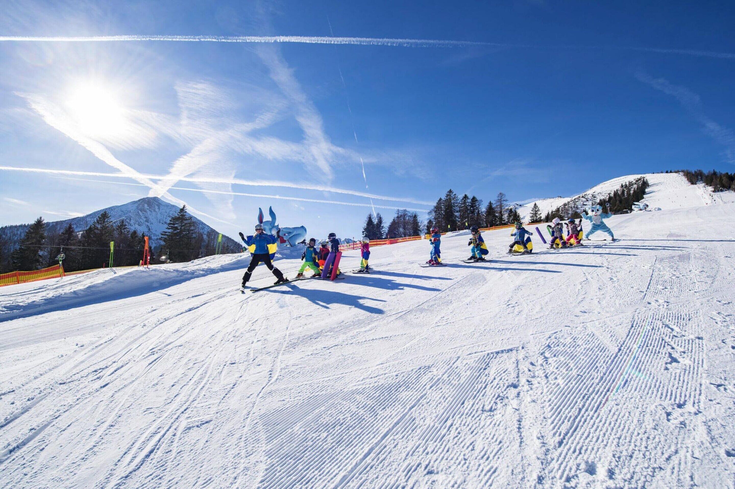 Ein verschneiter Skipisten mit Skifahrern und Snowboardern.
