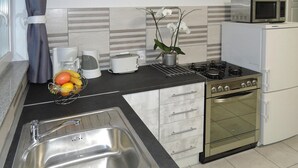 A kitchen with a stainless steel sink, a toaster, a microwave, a stove, and a refrigerator. - Holiday Flat in Kolczewo-70 qm for 6 Persons (gmina Wolin)