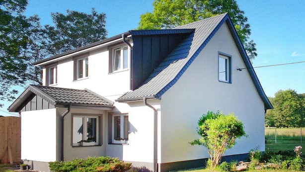 A two-story house with a sloped roof, a small porch, and a garden with shrubs and a tree. - Holiday Flat in Kolczewo-70 qm for 6 Persons (gmina Wolin)