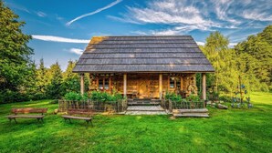 A rustic wooden cabin with a thatched roof, surrounded by a well-maintained lawn and trees. - Holiday Home in Belczna Near Klepnicko Lake (Łobez)