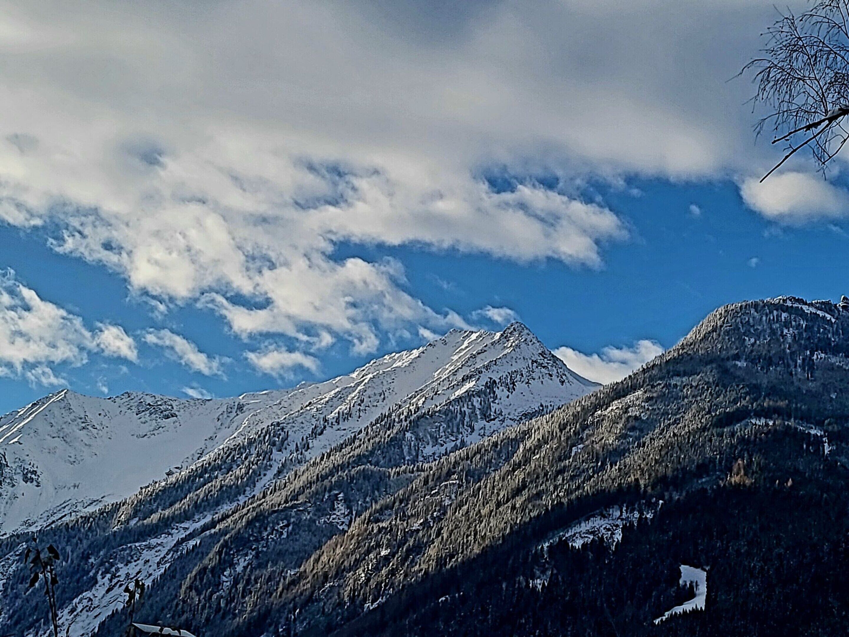 A mountain landscape with snow-covered peaks and a clear blue sky.