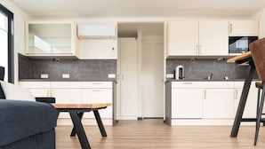 A modern kitchen with white cabinets, a wooden dining table, and a dark-colored sofa. - Hausboot in Boltenhagen (Boltenhagen)