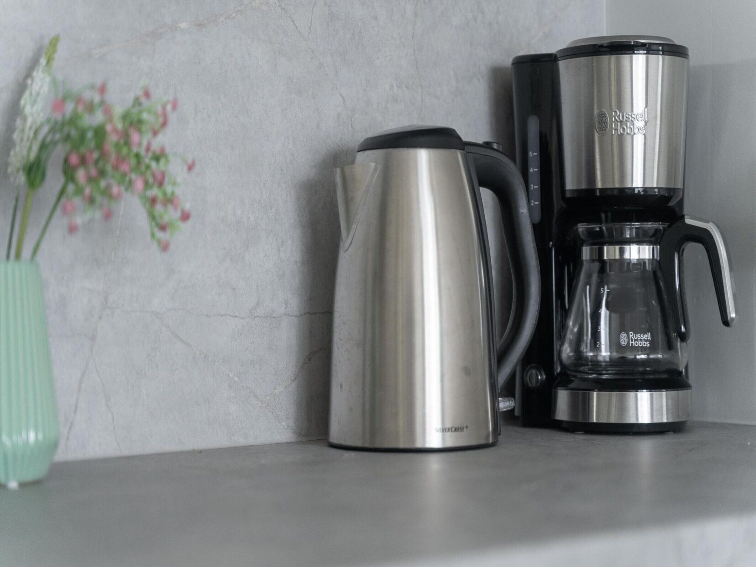 Una cafetera de acero inoxidable y un hervidor sobre una encimera.