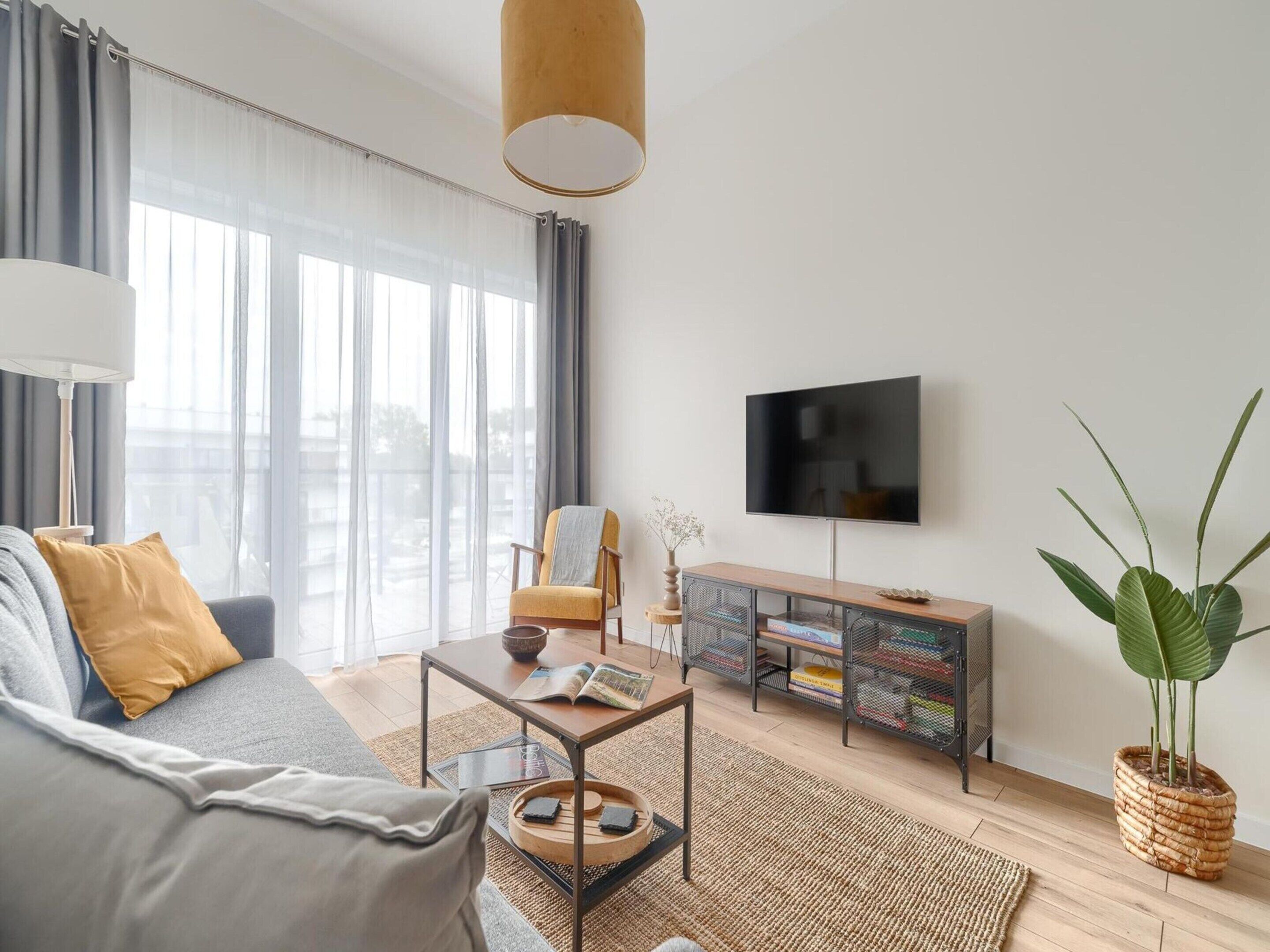 A modern living room with a sofa, coffee table, and a TV on a stand.