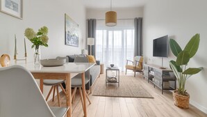 Una sala de estar moderna con comedor, un sofá, un televisor y una planta grande.