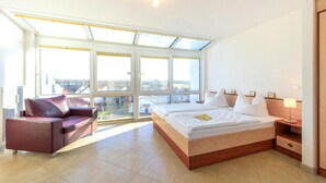 Una camera d'hotel moderna con un letto grande, una poltrona e un lucernario.
